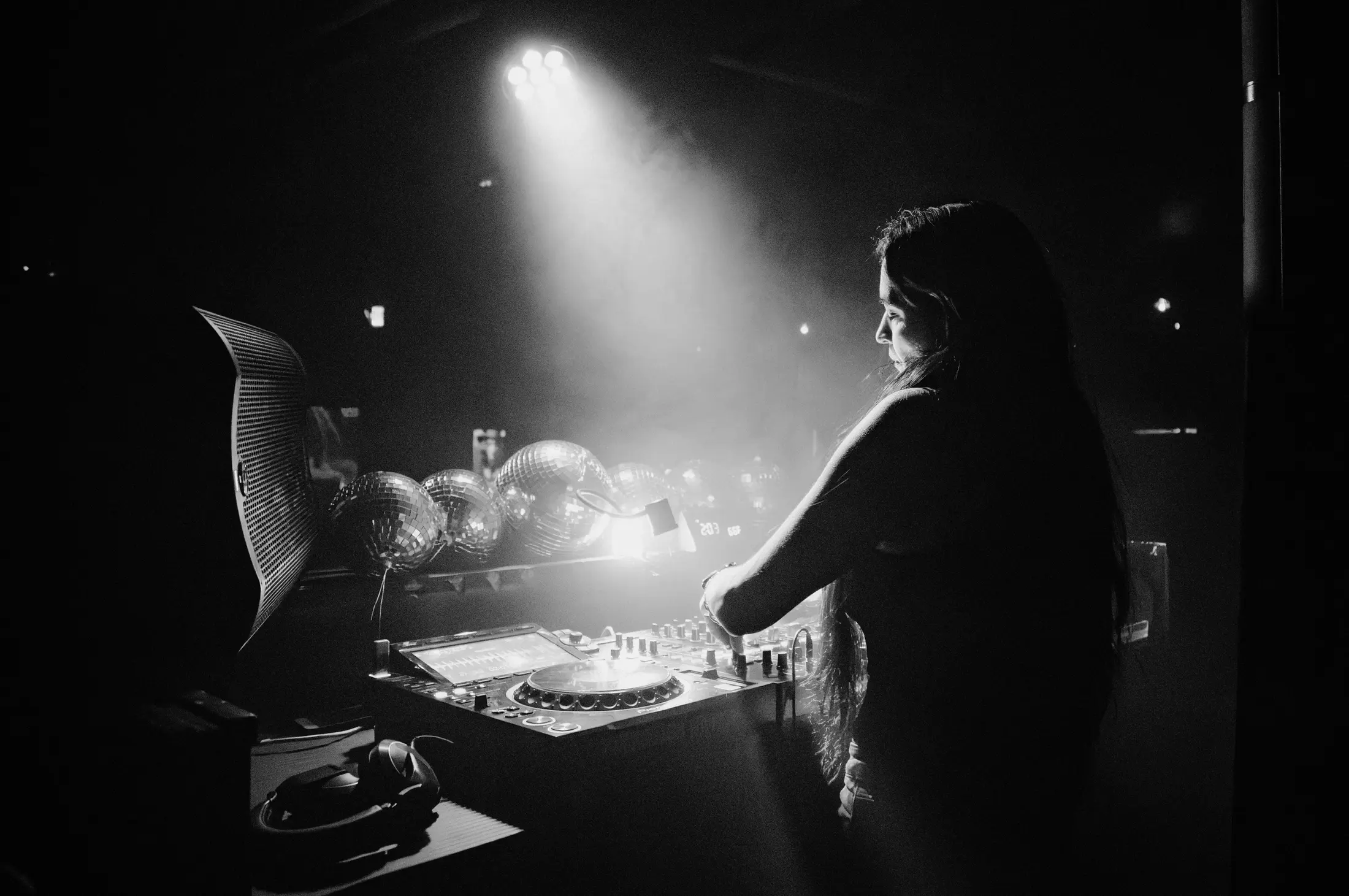 Susie Otto performing behind the decks in a beam of stage light